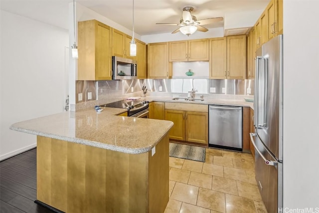 kitchen featuring sink, kitchen peninsula, ceiling fan, stainless steel appliances, and decorative backsplash