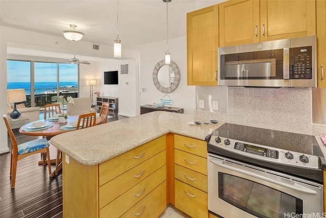 kitchen featuring backsplash, kitchen peninsula, stainless steel appliances, light stone countertops, and a water view