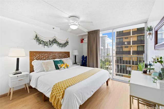 bedroom with access to outside, floor to ceiling windows, ceiling fan, and hardwood / wood-style floors