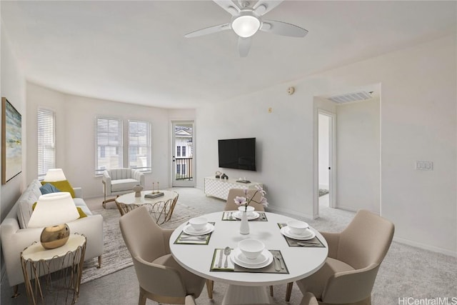 dining area with ceiling fan and light colored carpet