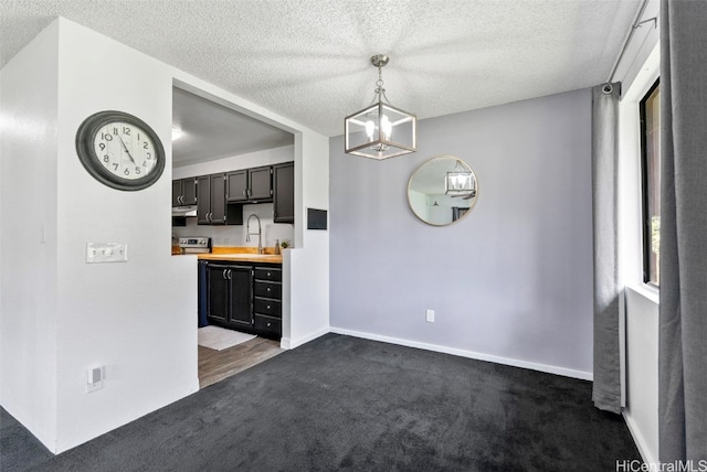 kitchen with dark carpet, sink, hanging light fixtures, a textured ceiling, and butcher block counters