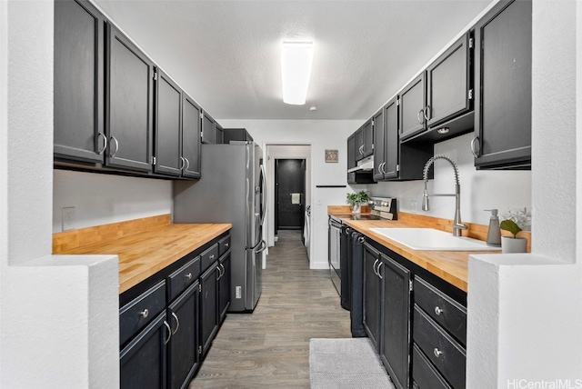 kitchen with stainless steel refrigerator, butcher block counters, electric range, sink, and light hardwood / wood-style floors