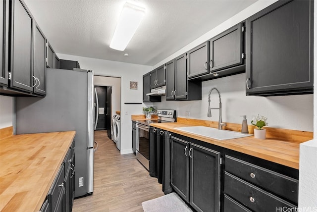 kitchen with washing machine and dryer, wooden counters, stainless steel appliances, and sink