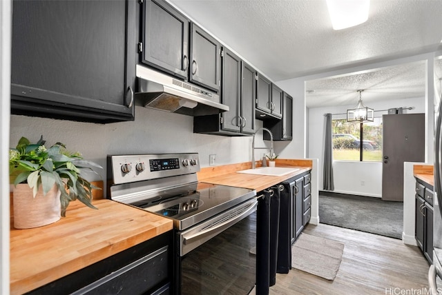 kitchen with extractor fan, sink, electric stove, pendant lighting, and butcher block countertops