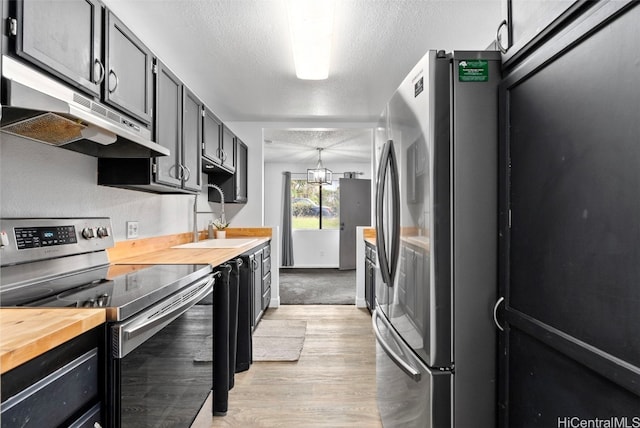 kitchen featuring wood counters, a textured ceiling, stainless steel appliances, sink, and hanging light fixtures