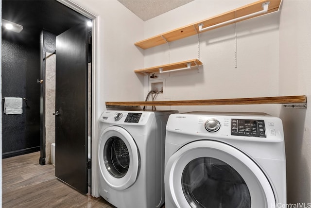 washroom with hardwood / wood-style floors, a textured ceiling, and separate washer and dryer