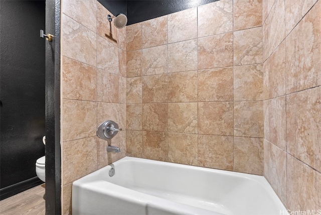 bathroom featuring tiled shower / bath combo and toilet