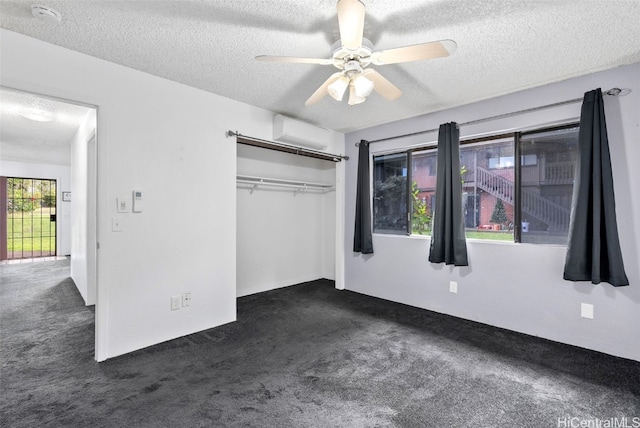 unfurnished bedroom with a wall mounted air conditioner, ceiling fan, dark carpet, and multiple windows