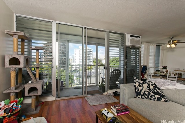 living room featuring hardwood / wood-style floors, a wall mounted air conditioner, floor to ceiling windows, ceiling fan, and a textured ceiling