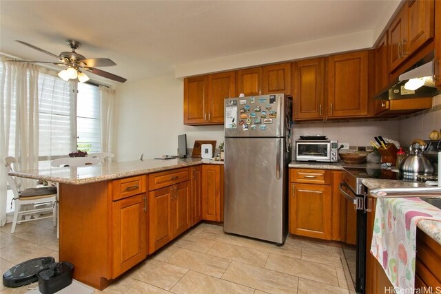 kitchen featuring ceiling fan, appliances with stainless steel finishes, tasteful backsplash, light stone counters, and kitchen peninsula