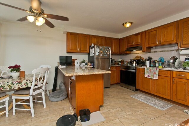 kitchen featuring light stone countertops, tasteful backsplash, stainless steel appliances, ceiling fan, and a breakfast bar area