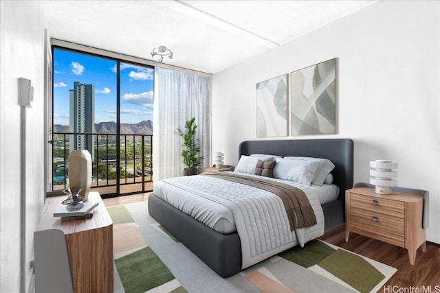 bedroom with expansive windows, wood-type flooring, and access to outside