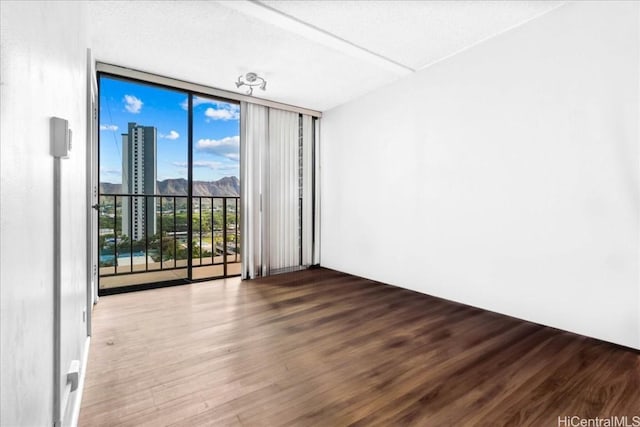 unfurnished room featuring floor to ceiling windows, wood-type flooring, and a textured ceiling