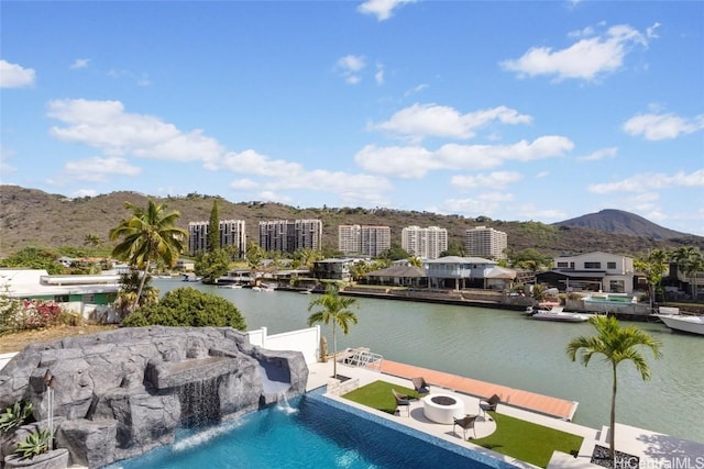 view of swimming pool with a patio area, a water and mountain view, and pool water feature