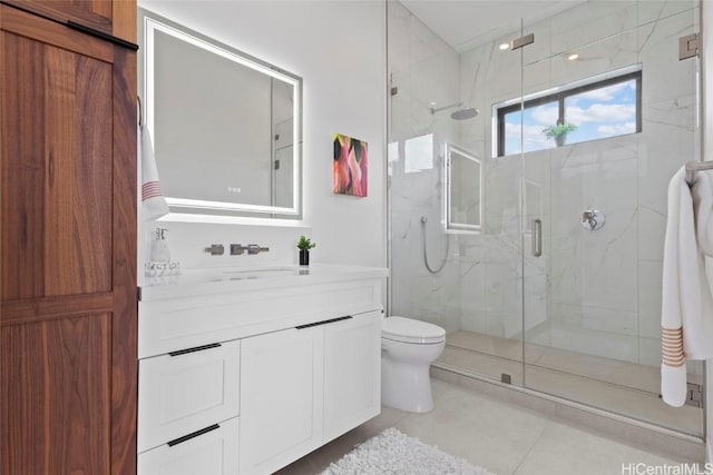 bathroom with a shower with shower door, vanity, tile patterned flooring, and toilet