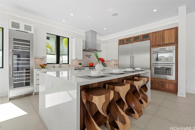 kitchen featuring beverage cooler, extractor fan, white cabinetry, stainless steel appliances, and a large island