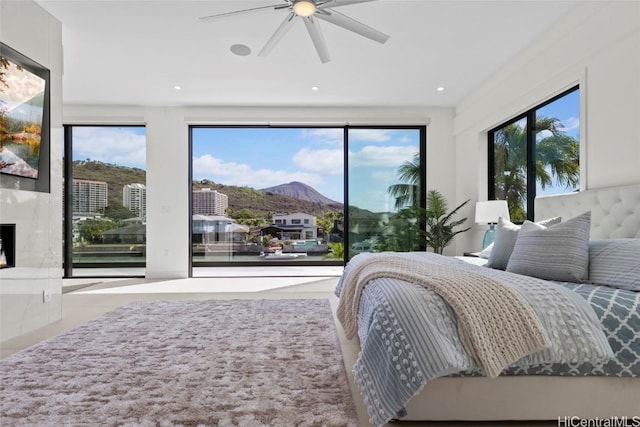 bedroom with ceiling fan, multiple windows, a mountain view, and a premium fireplace