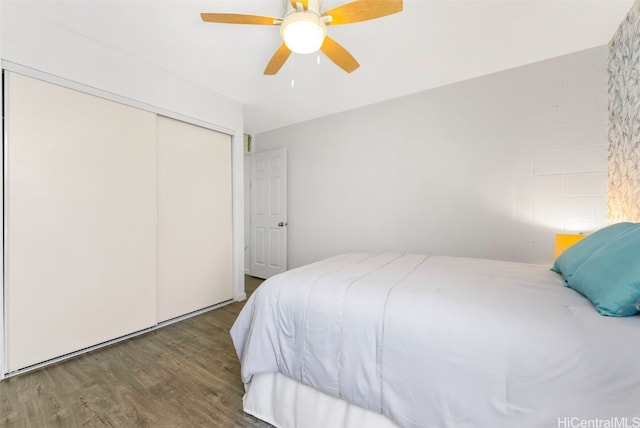 bedroom with ceiling fan, dark wood-type flooring, and a closet