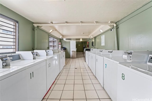 washroom featuring a textured ceiling, washing machine and dryer, and light tile patterned floors