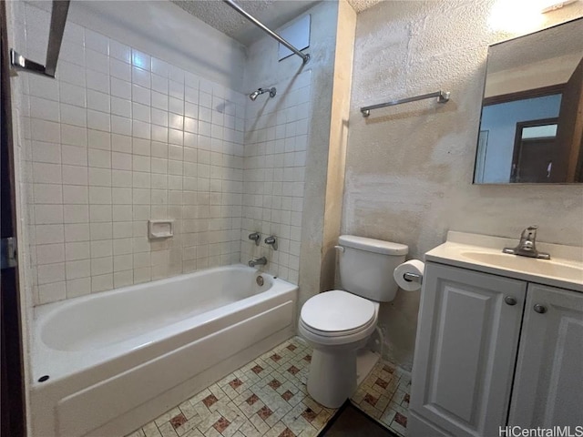 full bathroom with a textured ceiling, vanity, tiled shower / bath combo, and toilet