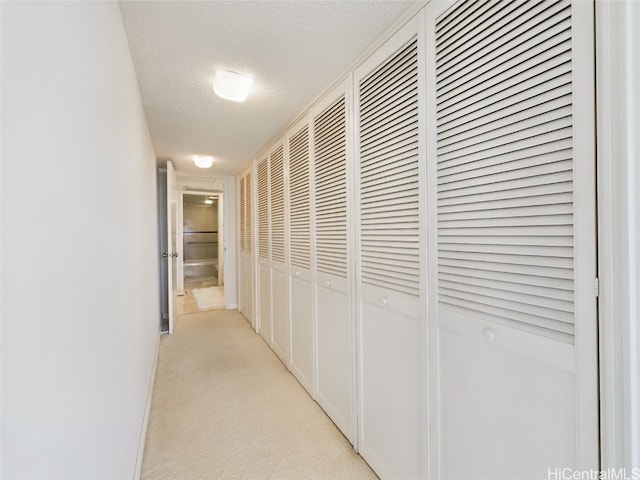 corridor featuring light colored carpet and a textured ceiling