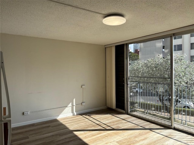 unfurnished room featuring floor to ceiling windows, wood-type flooring, and a textured ceiling