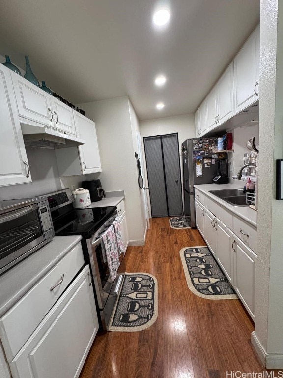 kitchen with stainless steel electric range oven, sink, dark hardwood / wood-style flooring, refrigerator, and white cabinets