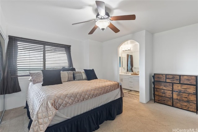 bedroom featuring connected bathroom, ceiling fan, and light colored carpet