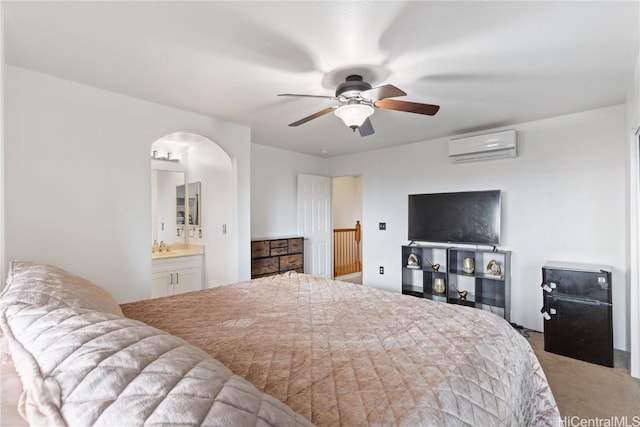 carpeted bedroom with ensuite bath, a wall mounted AC, and ceiling fan