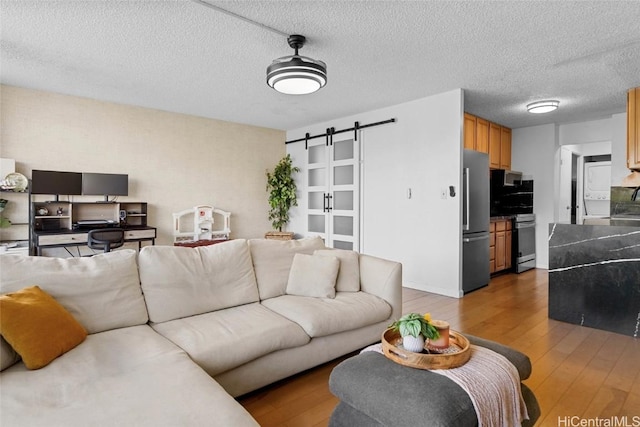 living room featuring a barn door, dark wood-type flooring, and a textured ceiling