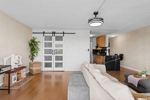 living room featuring dark hardwood / wood-style floors, a barn door, and a textured ceiling