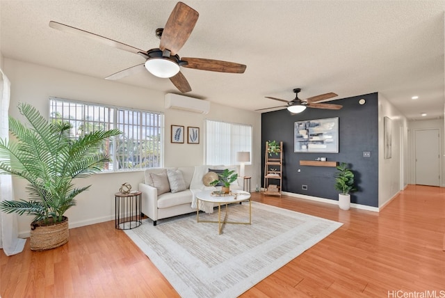 living area featuring ceiling fan, a wall unit AC, a textured ceiling, and hardwood / wood-style floors