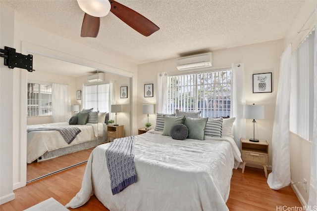 bedroom with ceiling fan, hardwood / wood-style flooring, and a wall unit AC