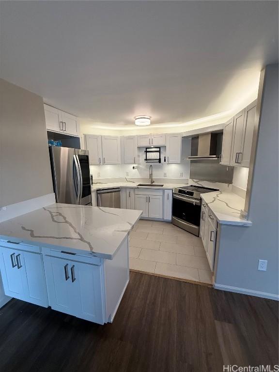 kitchen featuring sink, light stone counters, appliances with stainless steel finishes, kitchen peninsula, and white cabinets