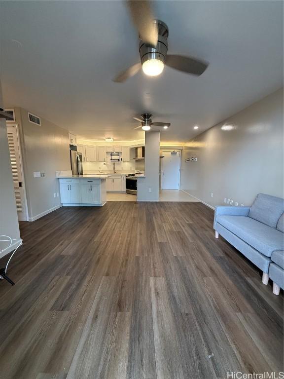 unfurnished living room featuring dark hardwood / wood-style flooring and ceiling fan