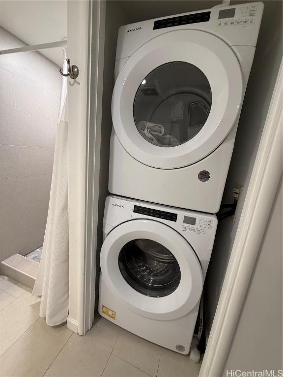 laundry room with stacked washer and clothes dryer and light tile patterned floors