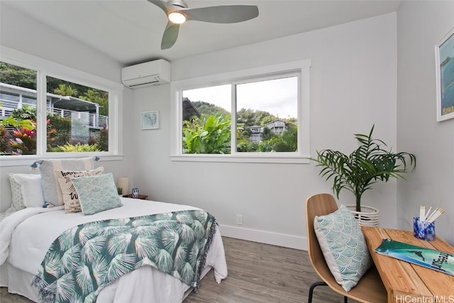 bedroom with ceiling fan, multiple windows, hardwood / wood-style floors, and a wall unit AC