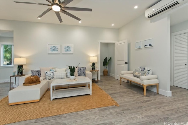 living room with ceiling fan, light wood-type flooring, and a wall mounted air conditioner