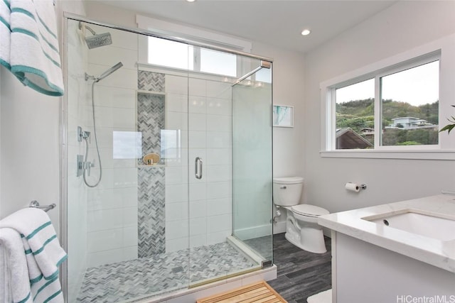 bathroom featuring toilet, a shower with door, hardwood / wood-style flooring, and vanity