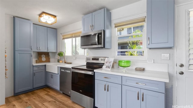 kitchen with sink, light hardwood / wood-style floors, and appliances with stainless steel finishes