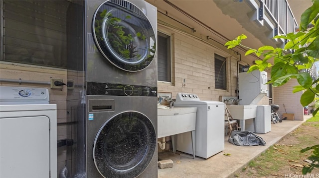 clothes washing area featuring independent washer and dryer, stacked washer and clothes dryer, and sink