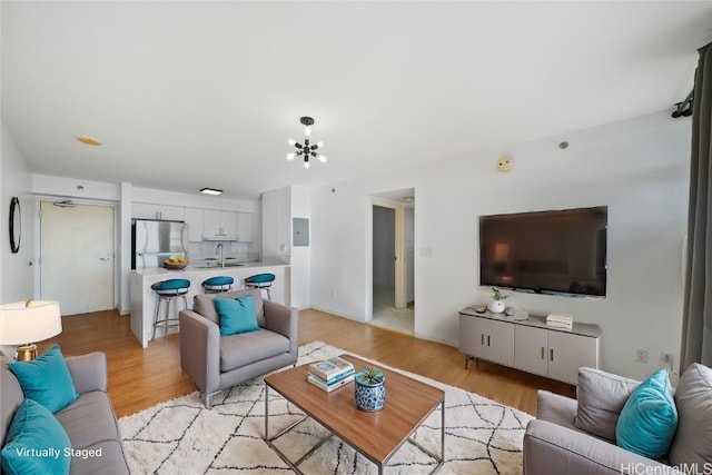 living room with light hardwood / wood-style floors, a notable chandelier, and sink