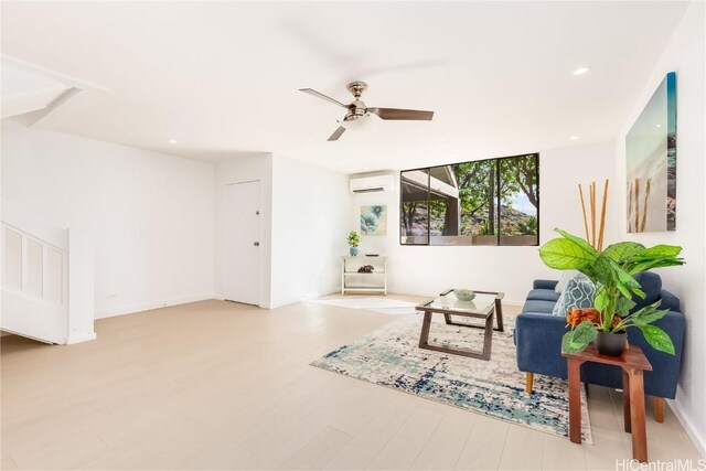 living room with an AC wall unit, ceiling fan, and light wood-type flooring