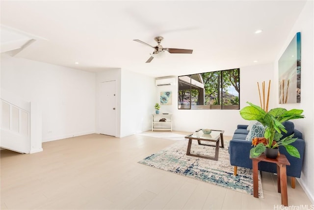 living area featuring light hardwood / wood-style flooring, ceiling fan, and a wall mounted AC