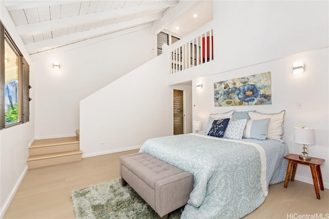 bedroom with hardwood / wood-style flooring, beamed ceiling, and high vaulted ceiling