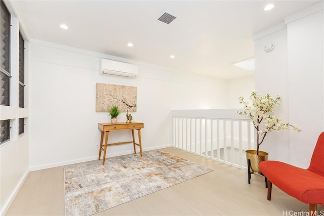 sitting room with an AC wall unit and hardwood / wood-style floors