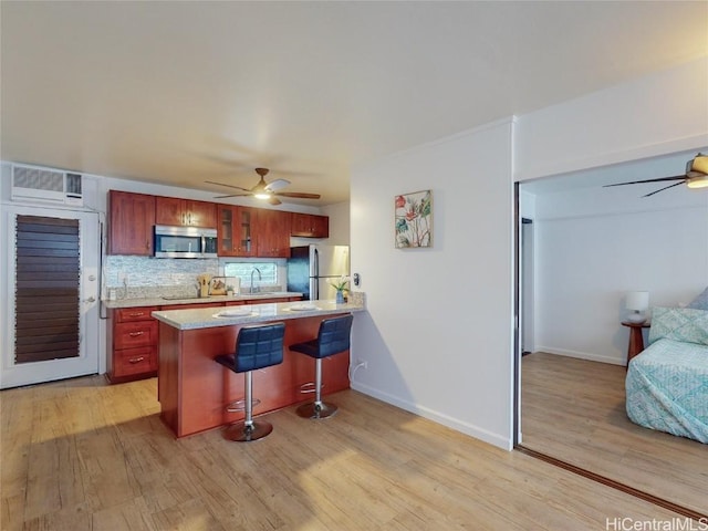 kitchen with kitchen peninsula, appliances with stainless steel finishes, decorative backsplash, and light hardwood / wood-style floors