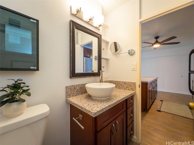 bathroom with hardwood / wood-style floors, vanity, toilet, and ceiling fan