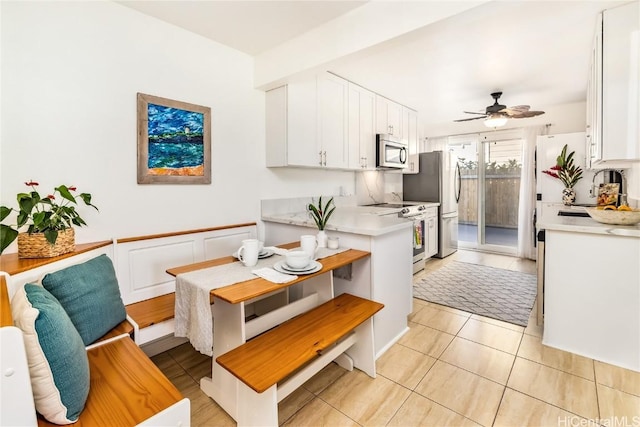 kitchen featuring white cabinets, sink, ceiling fan, light tile patterned floors, and appliances with stainless steel finishes