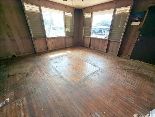 spare room featuring hardwood / wood-style floors, ceiling fan, and wooden walls